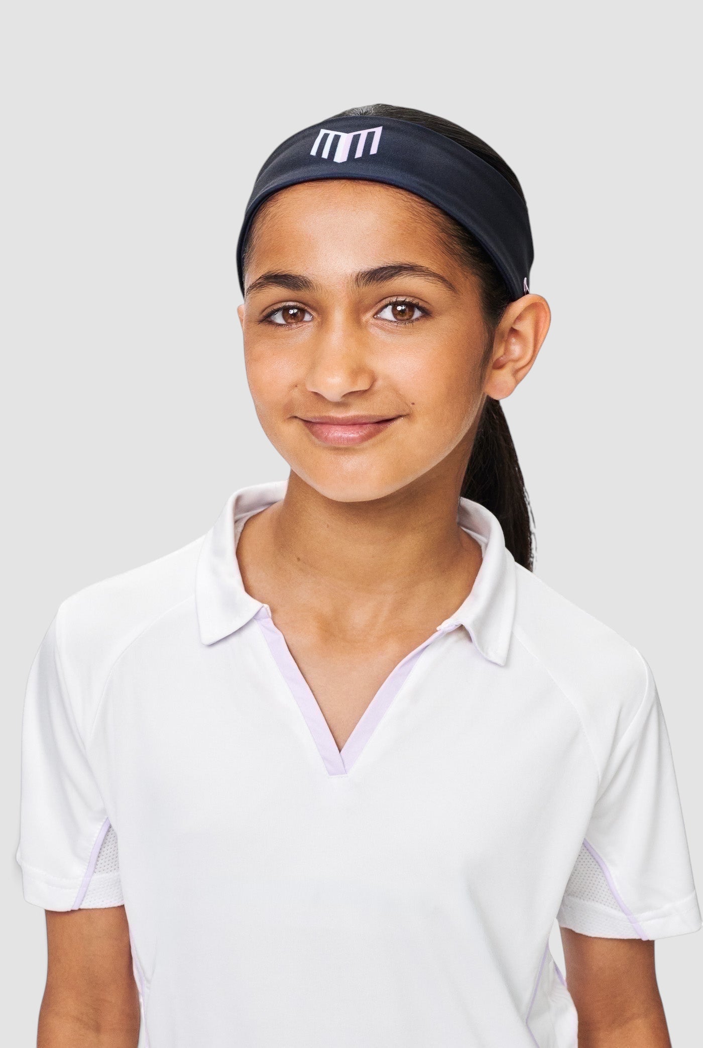 Maiden Cricket Bouncer Headband in black with white logo, worn by a young female cricketer in a white polo shirt.