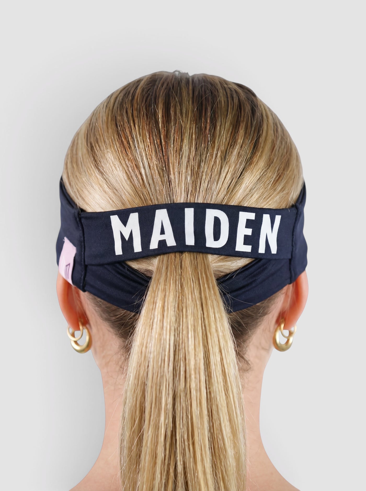 Maiden Cricket Bouncer Headband in navy blue with ponytail opening worn by a woman with blonde hair