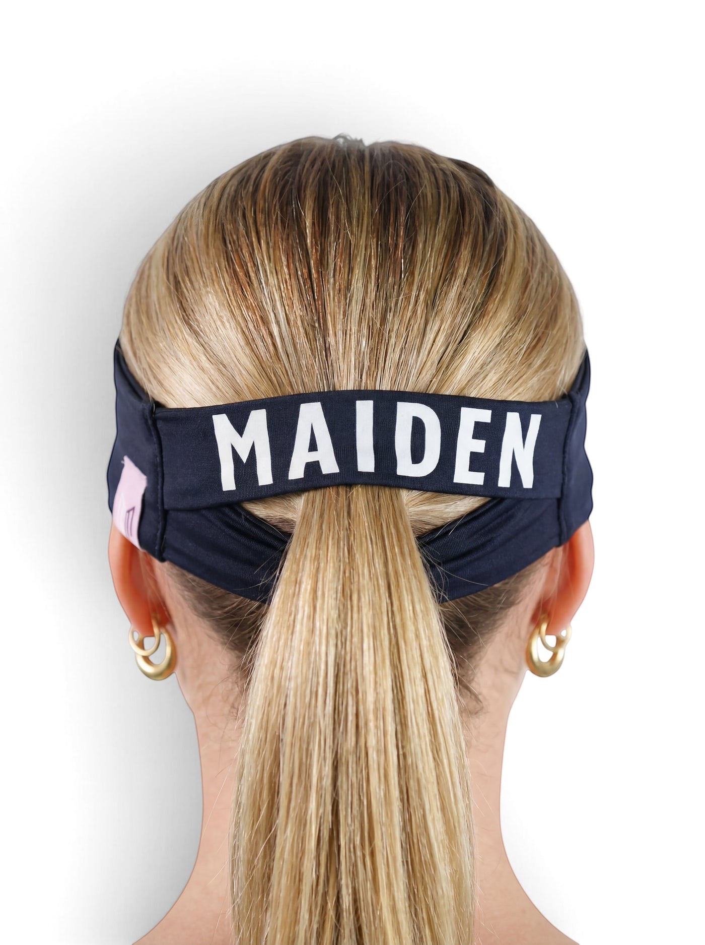 Maiden Cricket Bouncer Headband in navy blue with a ponytail opening, worn by a woman with blonde hair.