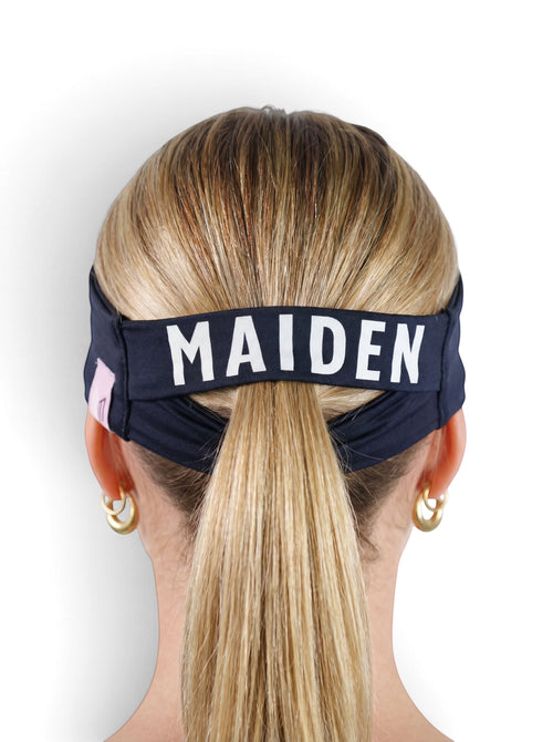 Maiden Cricket Bouncer Headband in navy blue with a ponytail opening, worn by a woman with blonde hair.