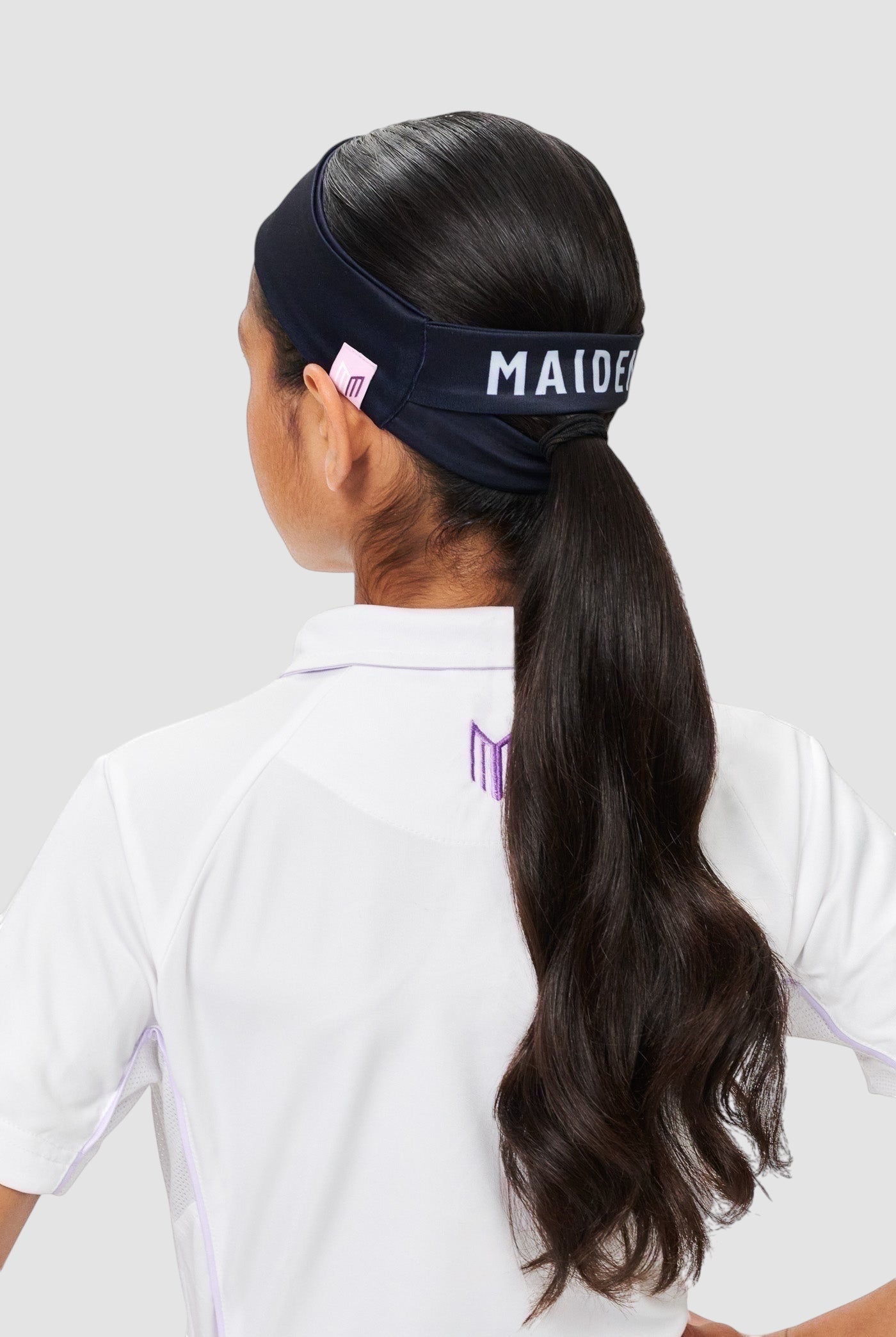 Maiden Cricket Bouncer headband in navy blue with ponytail opening worn by a player with long dark hair
