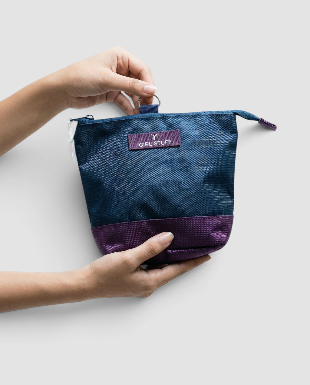 Maiden Cricket detachable essentials pouch in navy and purple, held by hands, featuring a Girl Stuff label.