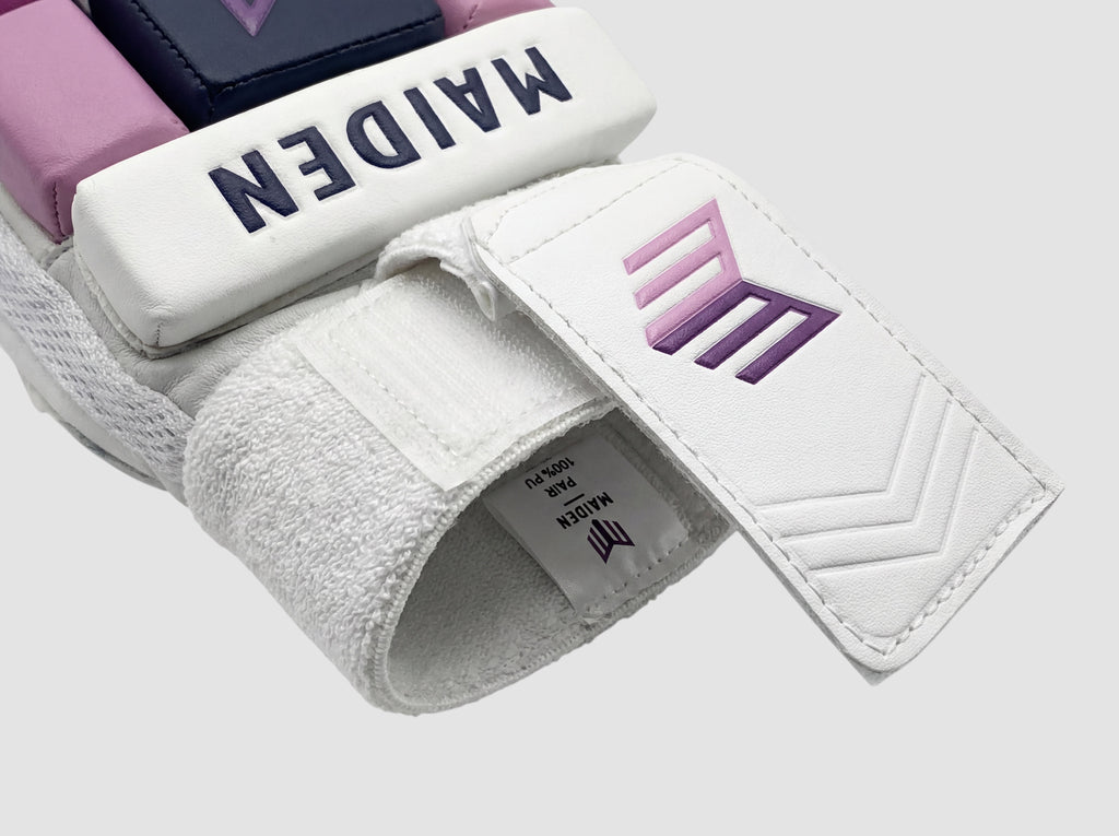 Maiden Cricket girls batting glove featuring white PU, navy and pink padding, and a moisture-absorbing sweatband.