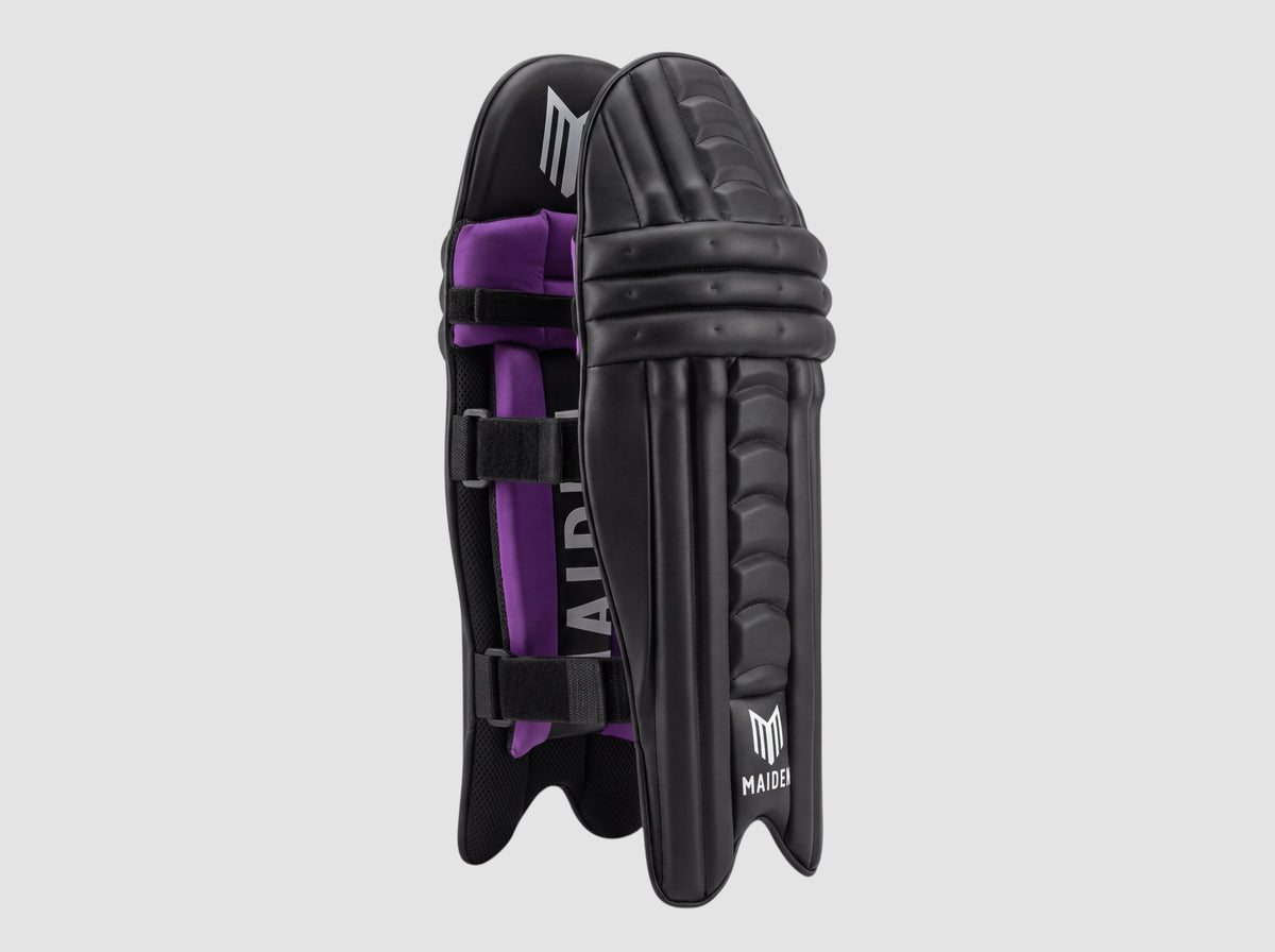 Maiden Cricket girls' black batting pads with ergonomic knee curve, purple interior padding, and secure straps.