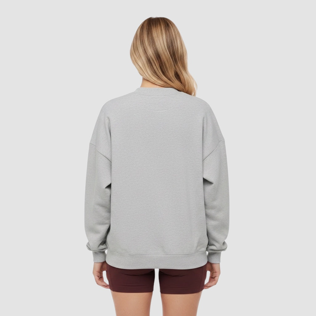 Back view of a woman wearing a Maiden Cricket heather grey crewneck sweatshirt with ribbed cuffs and hem.