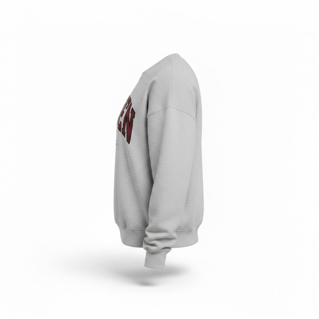 Maiden Cricket heather grey crewneck sweatshirt with maroon and black collegiate graphic, side view