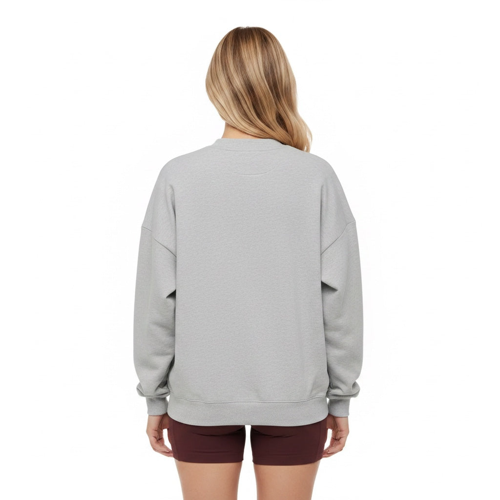 Back view of a woman wearing a Maiden Cricket heather grey crewneck sweatshirt with ribbed cuffs and hem.
