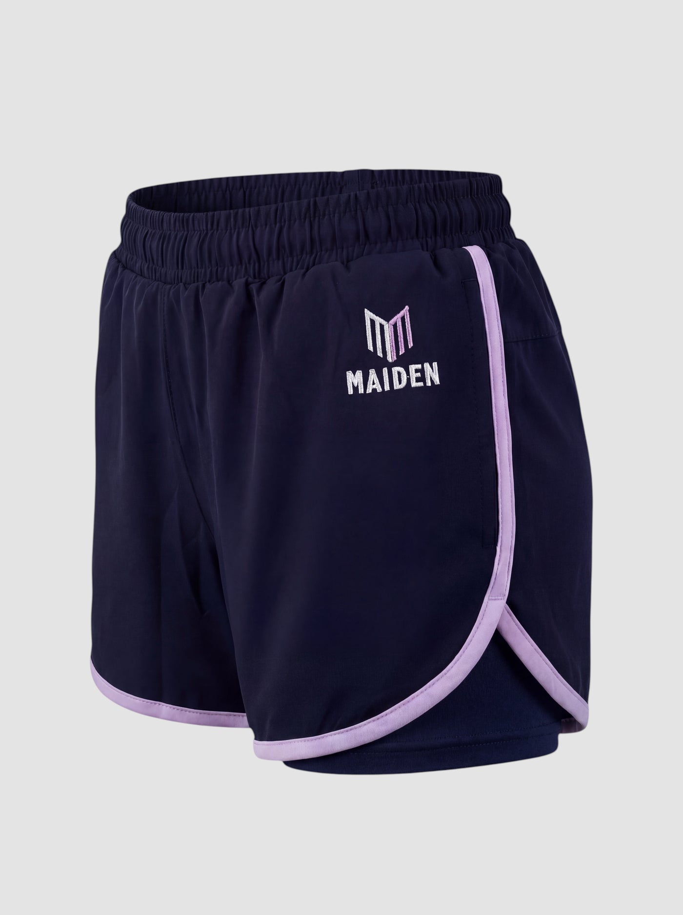 Maiden Cricket navy blue athletic shorts for women with light purple trim, built-in undershorts, and logo detail.