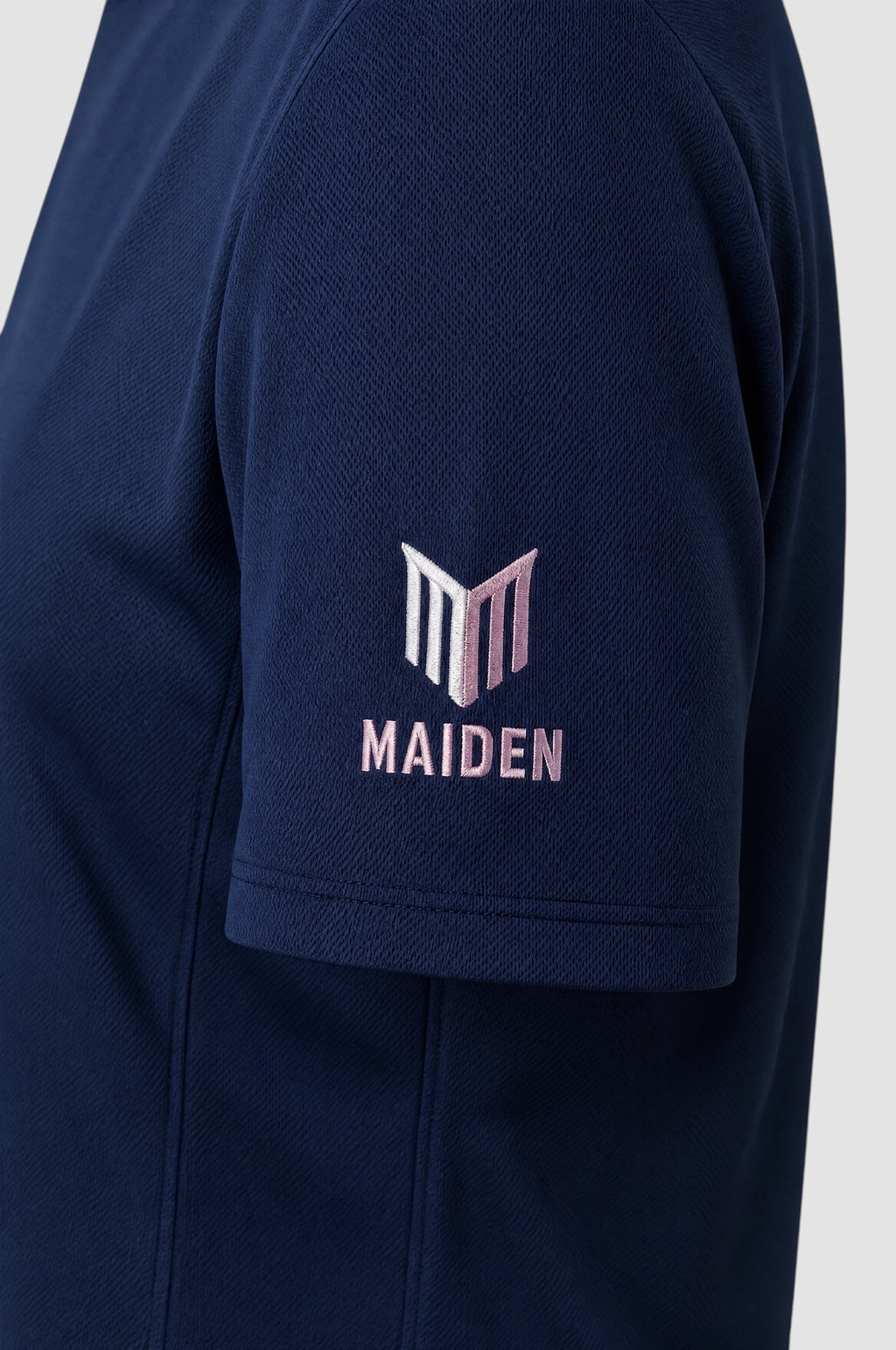 Close-up of the navy blue Maiden Cricket Women's World Cup t-shirt sleeve featuring a pink and white logo embroidery.