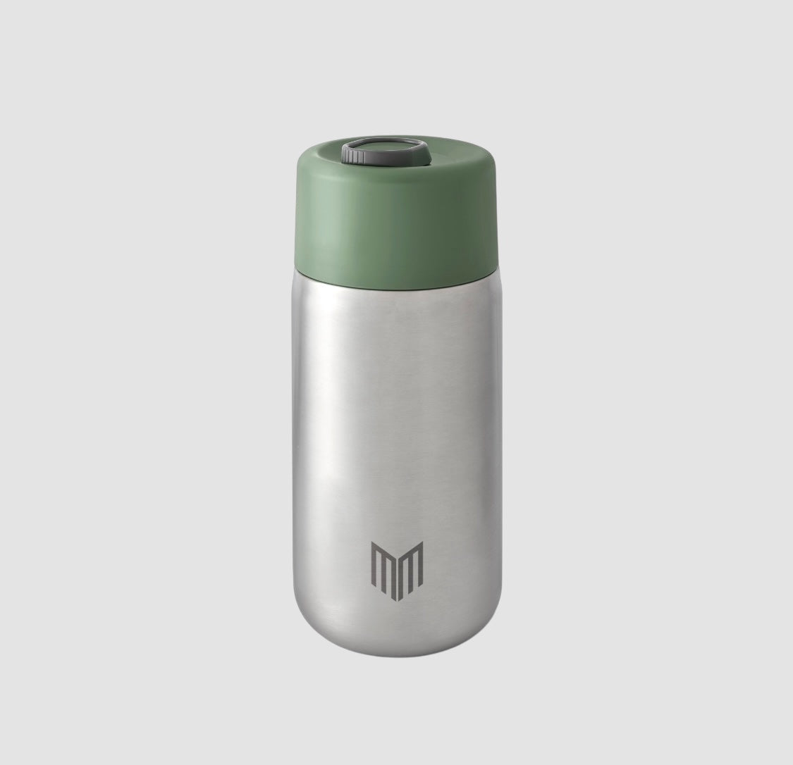 Maiden Cricket x Black+Blum stainless steel travel mug in silver with a sage green leak-proof lid and logo detail.