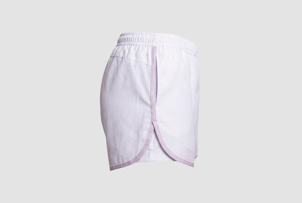 Maiden Cricket white athletic shorts with lavender trim, curved hem, and side pockets for women's sports training.