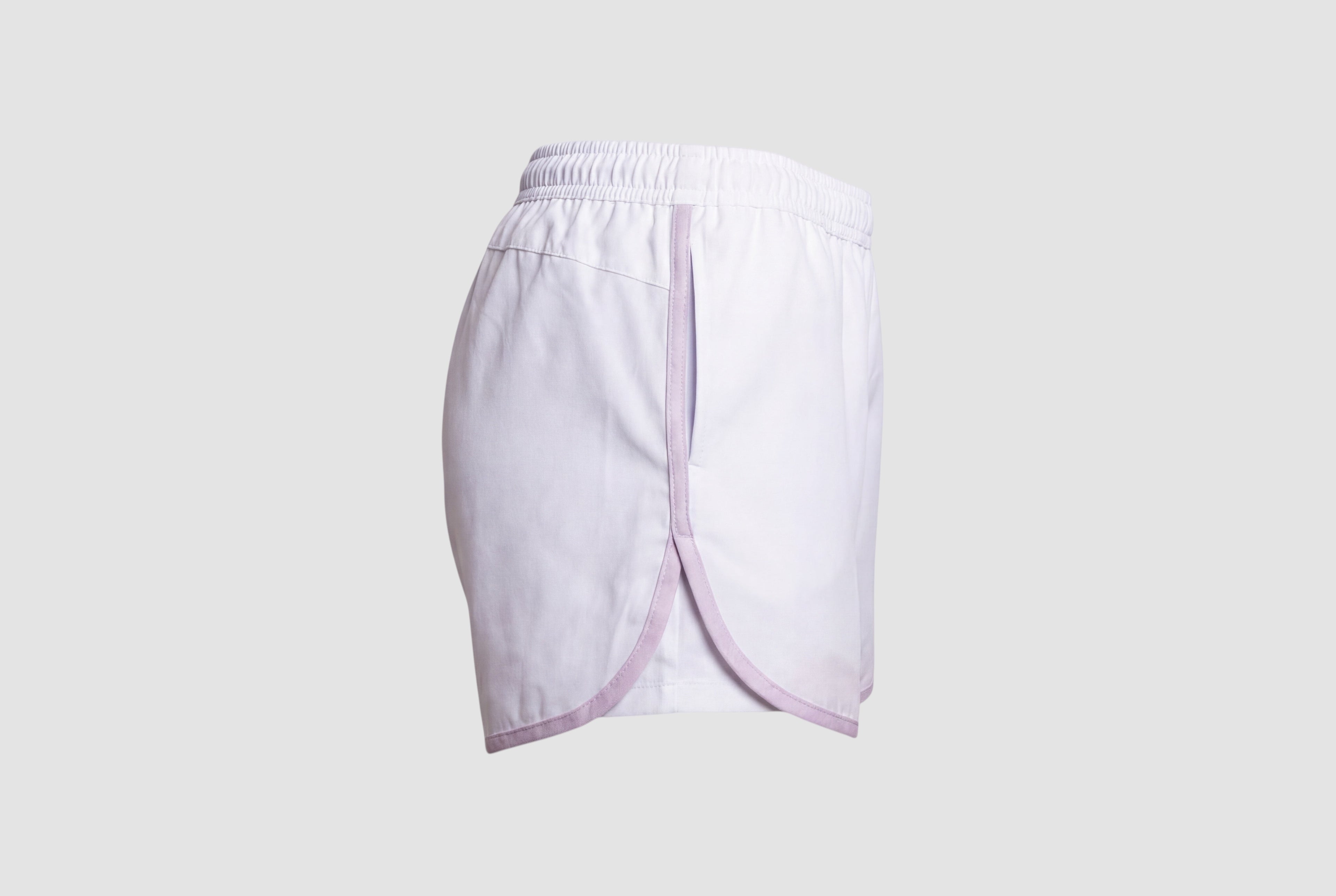 Maiden Cricket white athletic shorts with lavender trim, curved hem, and side pockets for women's sports training.