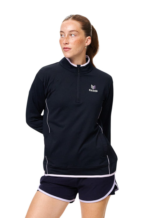 Maiden Cricket women's black quarter-zip midlayer with light purple trim and logo, worn by a model.