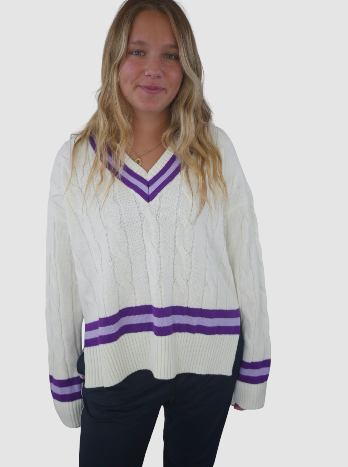 Maiden Cricket women's oversized white cable knit jumper with purple V-neck and striped hem and cuff detailing.