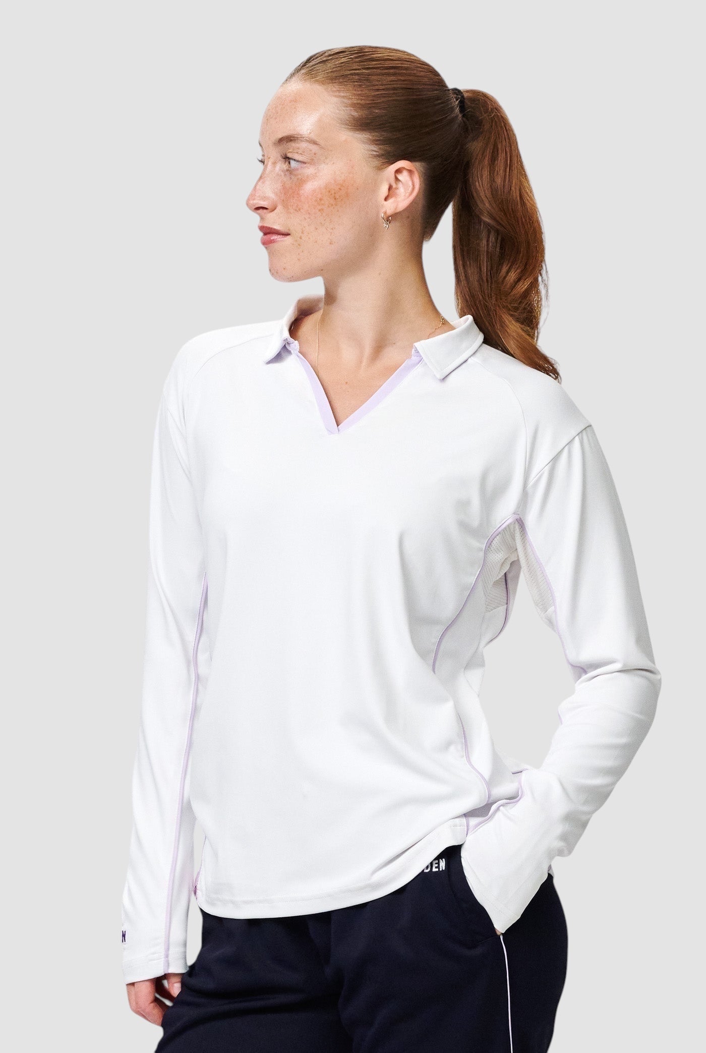 Maiden Cricket women's white long-sleeve cricket top with a polo collar, mesh underarm panels, and light purple trim.
