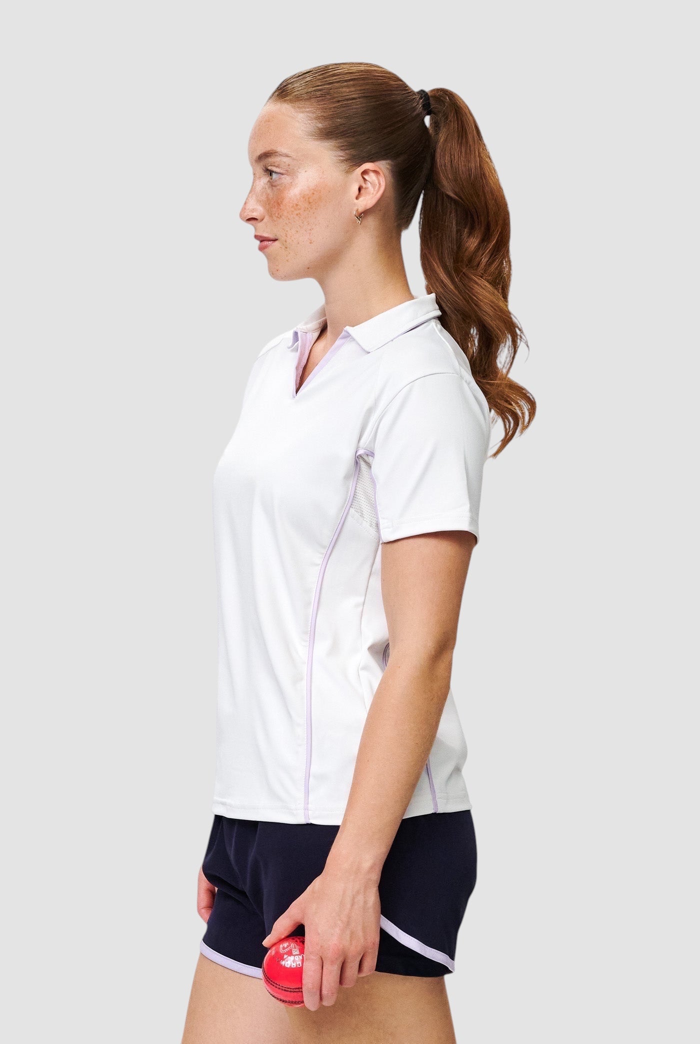Maiden Cricket women's white performance V-neck cricket top with mesh side panels worn by a female athlete