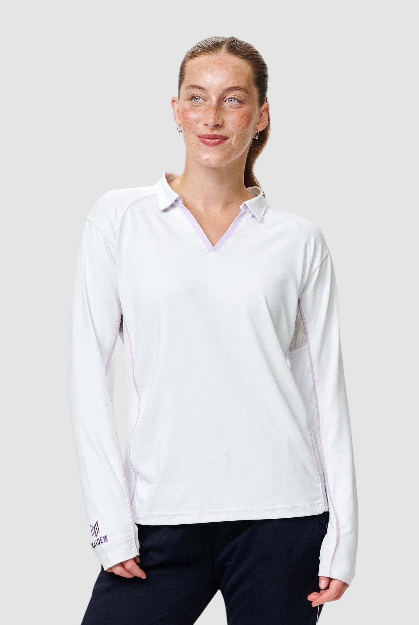 Maiden Cricket women's white long-sleeve cricket top with a v-neck collar and purple trim details.