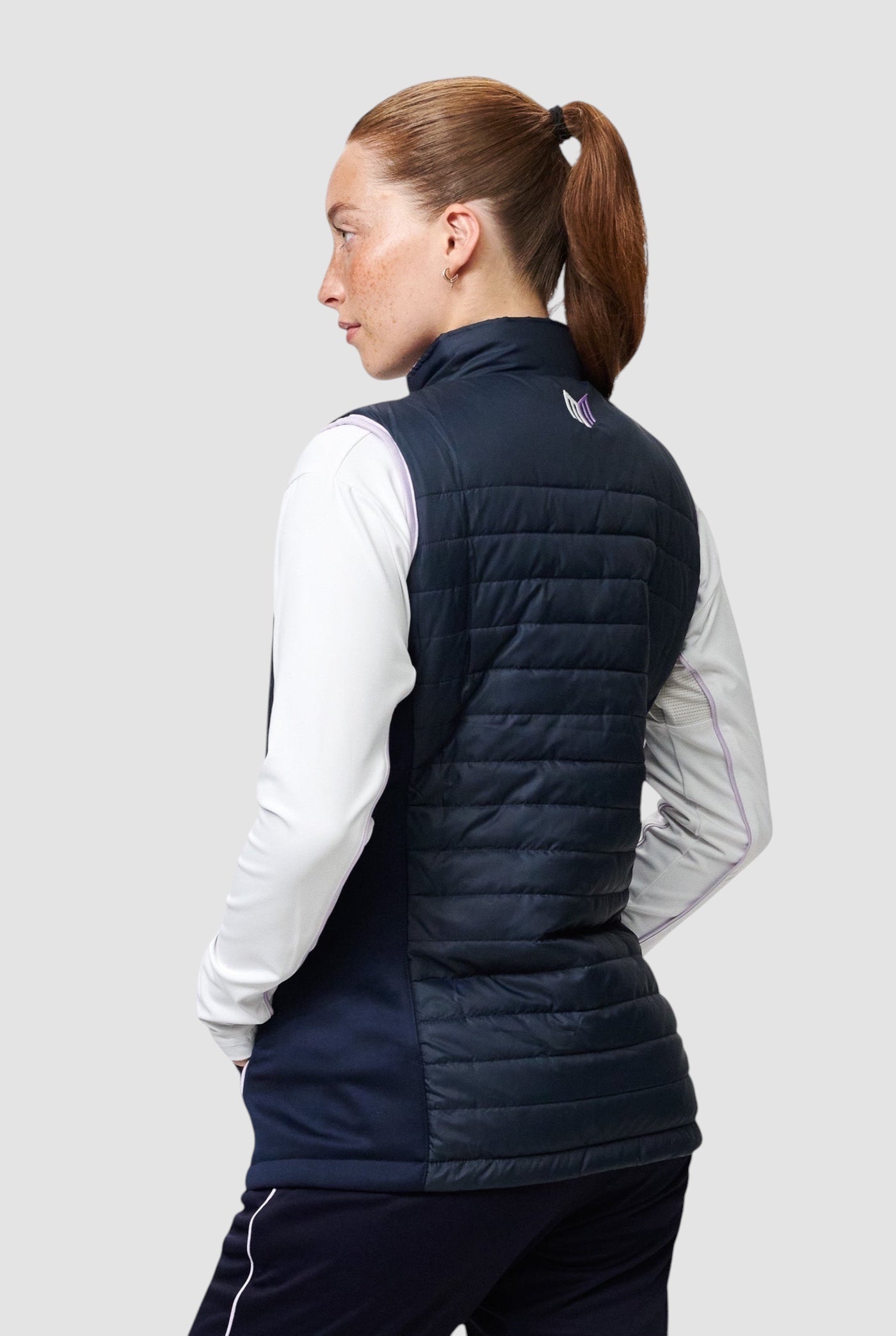 Maiden Cricket Yorker Gilet for women in navy with stretch side panels, worn over a white long-sleeve base layer.