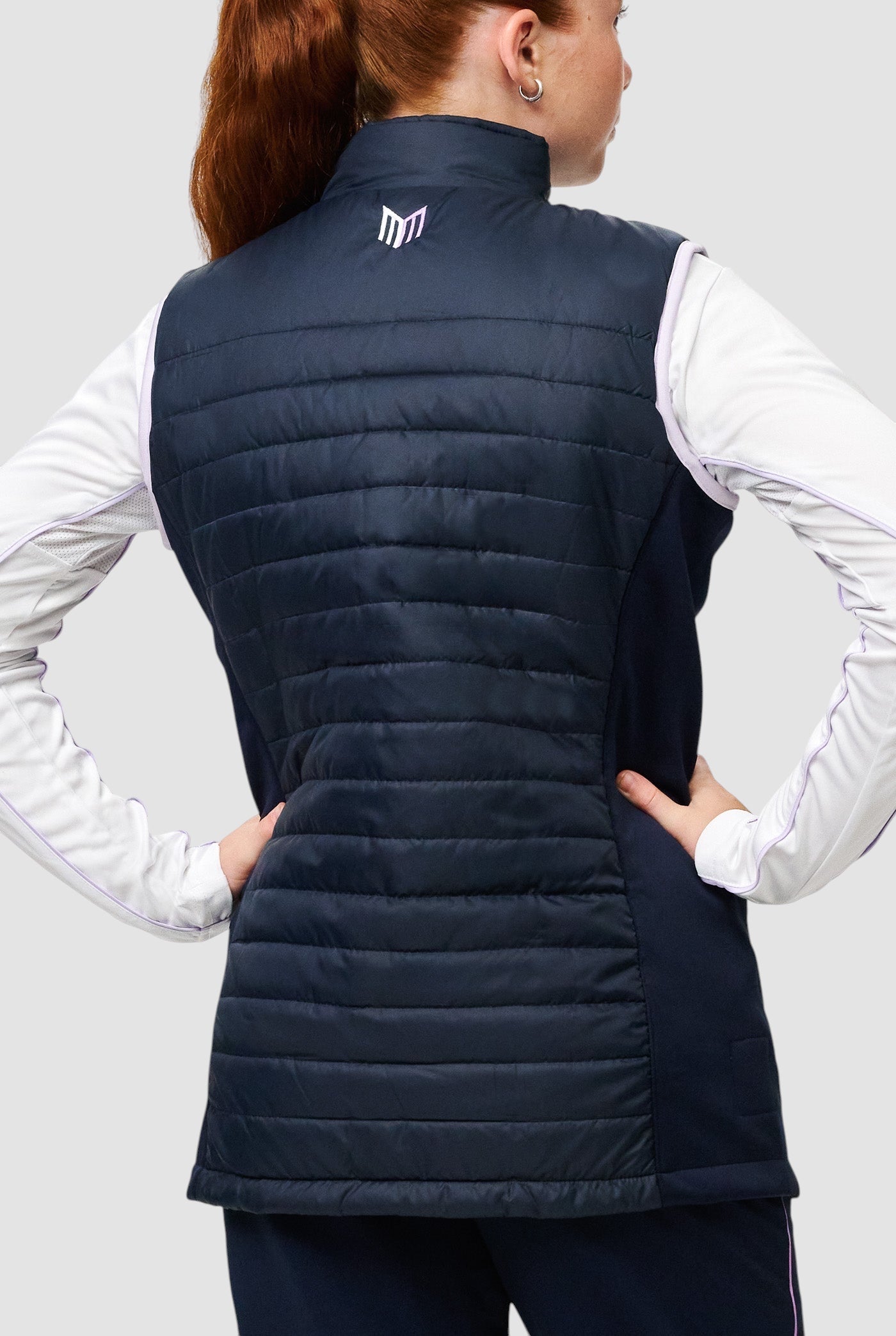 Back view of a girl wearing a navy Maiden Cricket Yorker Gilet with stretch side panels and a high collar